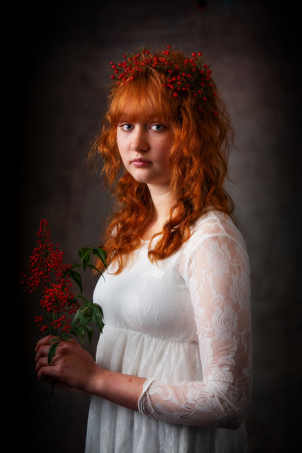 Teen portrait of a red haired girl holding red berries in a white dress.
