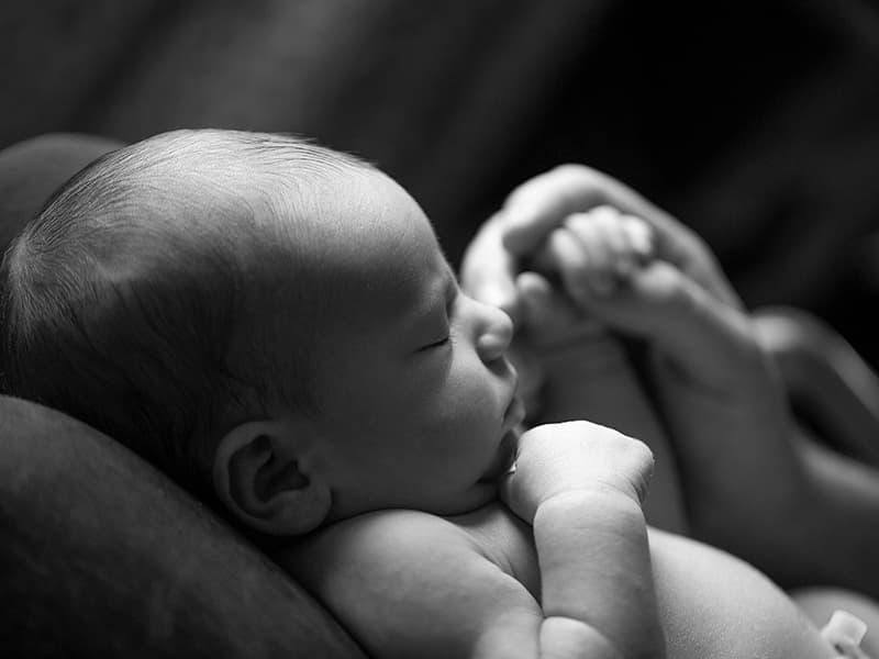 Close up black and white photograph of a newborn babys hands and face.