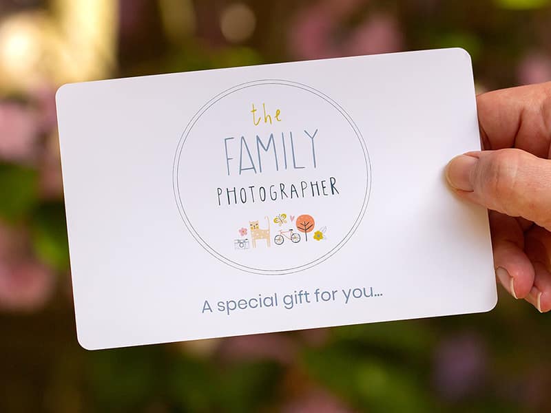 Picture of a hand holding a family photographer gift voucher.
