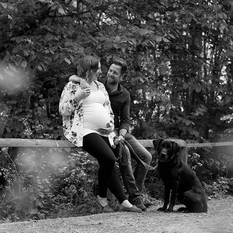 B& W portrait of a couple with a black labrador