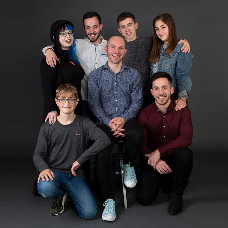 Group of seven siblings shot as a group against a grey background in the studio