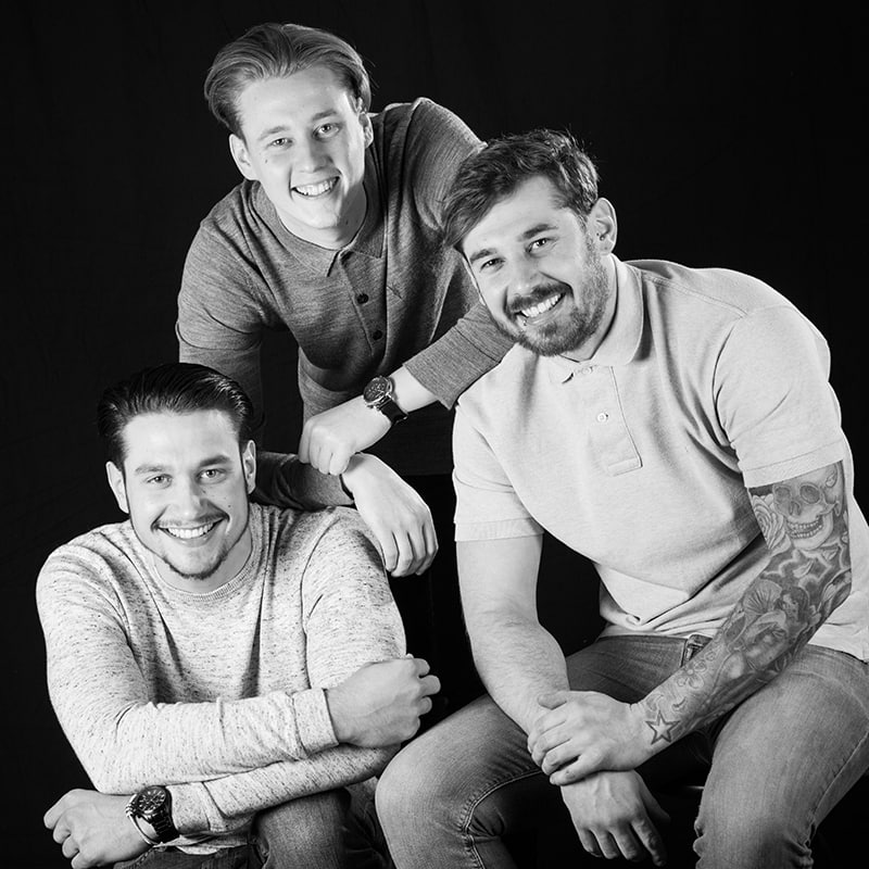 Black & white image of three adult brothers ina  group studio photo shoot.
