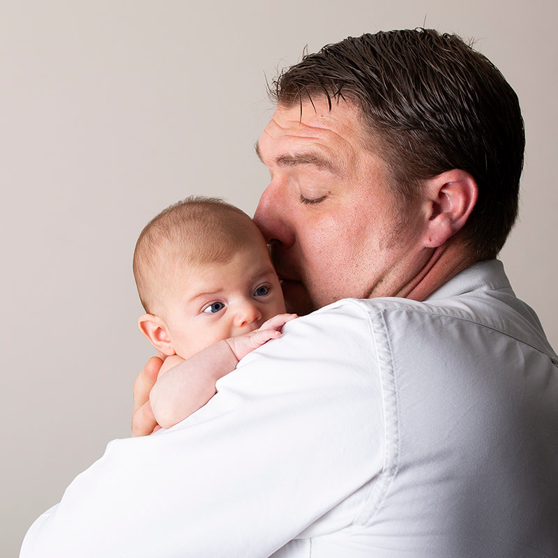 Close up of newborn baby being cuddled by her dad