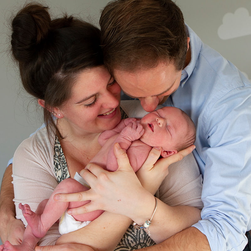 Close up shot of parents cuddling newborn baby at home