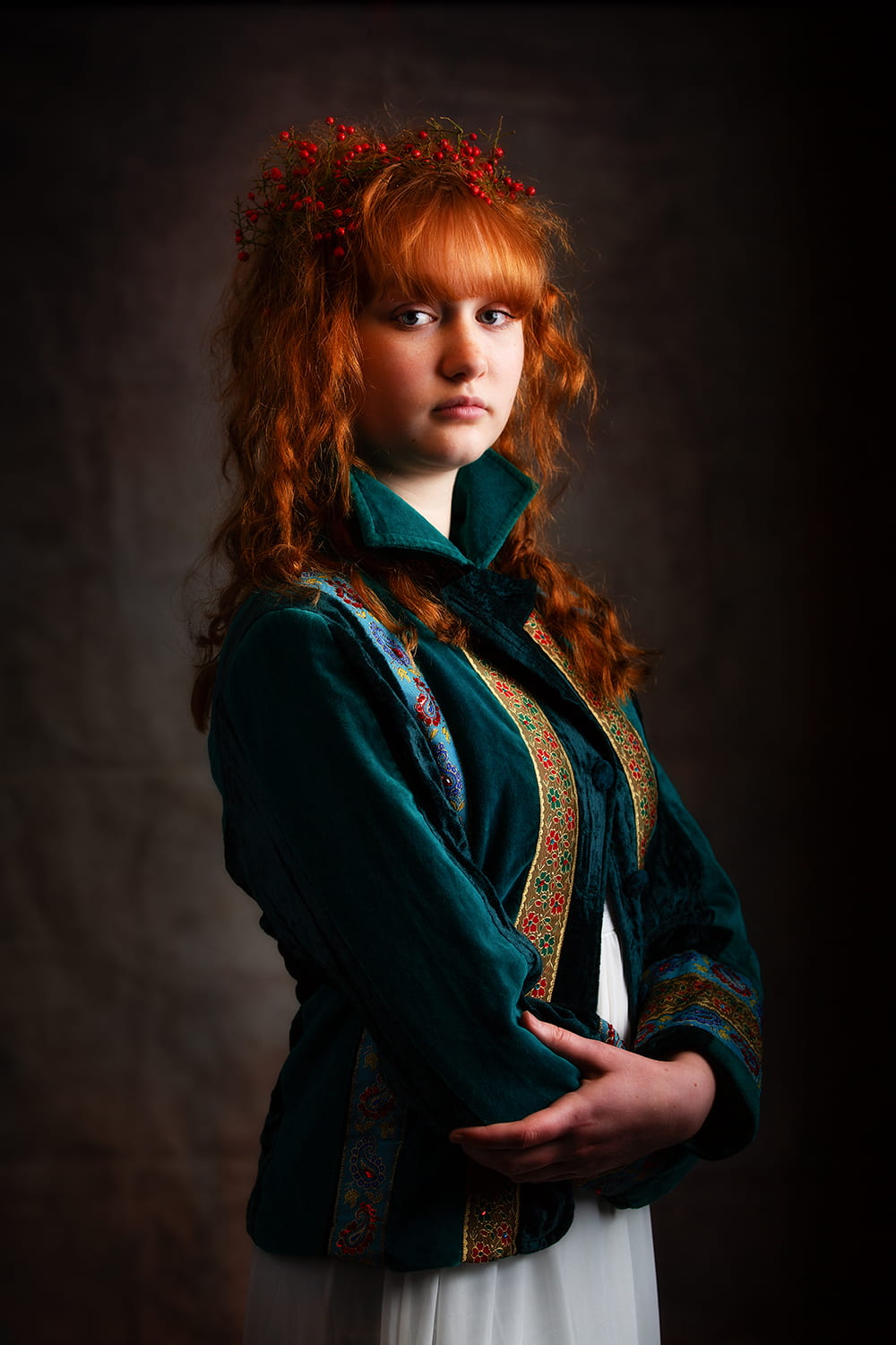 Portrait of a teenage girl with red hair wearing a green jacket with red berries in her hair.