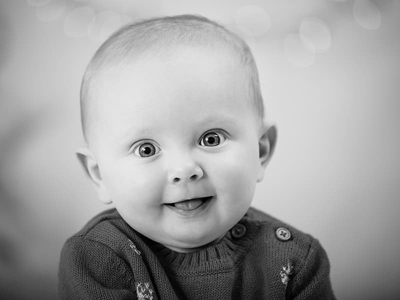 Close up portrait of a baby about six months old looking straight at the camera smiling.